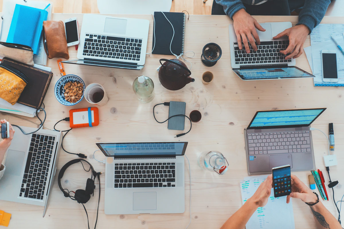 Pessoas trabalhando juntas em uma mesa com computadores e anotações